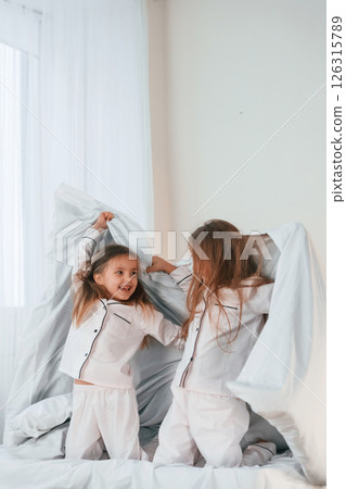 Girls are on the bed. Two little kids are playing and having fun together in domestic room Girls are on the bed. Two little kids are playing and having fun together in domestic room 126315789