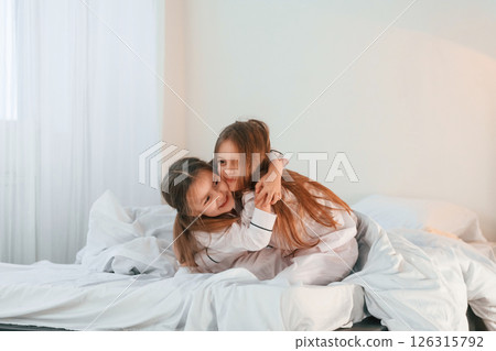 Girls are on the bed. Two little kids are playing and having fun together in domestic room Girls are on the bed. Two little kids are playing and having fun together in domestic room 126315792
