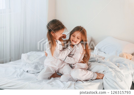 Girls are on the bed. Two little kids are playing and having fun together in domestic room Girls are on the bed. Two little kids are playing and having fun together in domestic room 126315793
