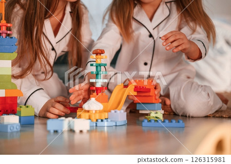 Many of the blocks of plastic construction toys. Two little girls are playing and having fun together in domestic room Many of the blocks of plastic construction toys. Two little girls are playing and having fun together in domestic room 126315981