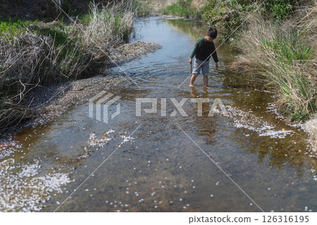 一個男孩在春日的陽光下在河裡玩耍 126316195