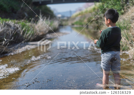 一個男孩在春日的陽光下在河裡玩耍 126316329