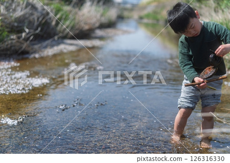 一個男孩在春日的陽光下在河裡玩耍 126316330