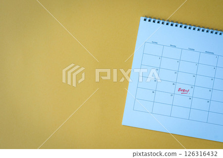 Calendar page with event reminder, on top of yellow surface. 126316432