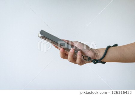 Woman holding a phone with a wrist strap. 126316433