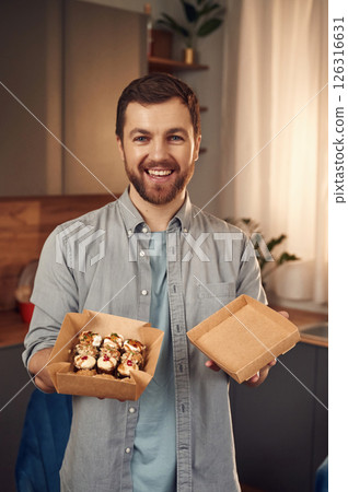 Sushi in the paper eco box. Man in casual clothes is indoors 126316631