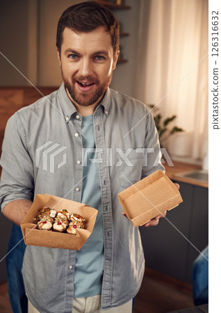 Sushi in the paper eco box. Man in casual clothes is indoors Sushi in the paper eco box. Man in casual clothes is indoors 126316632
