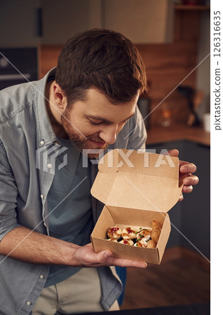 Sushi in the paper eco box. Man in casual clothes is indoors Sushi in the paper eco box. Man in casual clothes is indoors 126316635