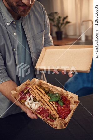 Man is holding paper eco box with food in it. Meat, cucumbers and vegetables 126316638