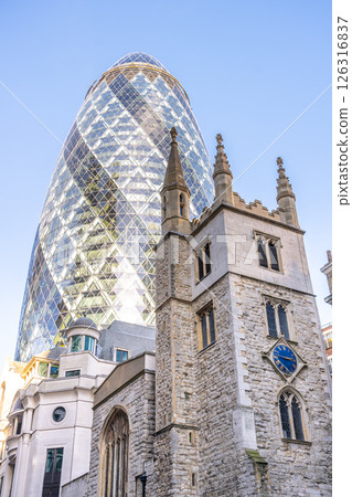 Old St Andrew Undershaft Church stands prominently beside the modern Gherkin building, showcasing the architectural evolution in London's City. Old St Andrew Undershaft Church stands prominently beside the modern Gherkin building, showcasing the architectural evolution in London's City. 126316837