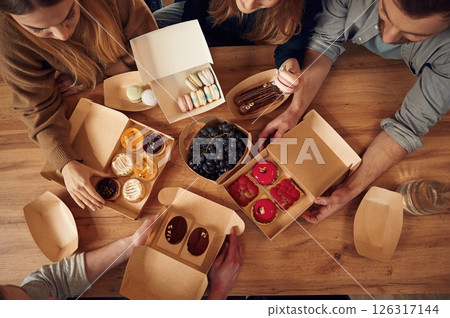 Top view of table with food on it, hands of the people taking it, eating. Macarons, blueberries, desserts, pastry meal Top view of table with food on it, hands of the people taking it, eating. Macarons, blueberries, desserts, pastry meal 126317144