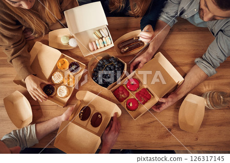 Top view of table with food on it, hands of the people taking it, eating. Macarons, blueberries, desserts, pastry meal Top view of table with food on it, hands of the people taking it, eating. Macarons, blueberries, desserts, pastry meal 126317145