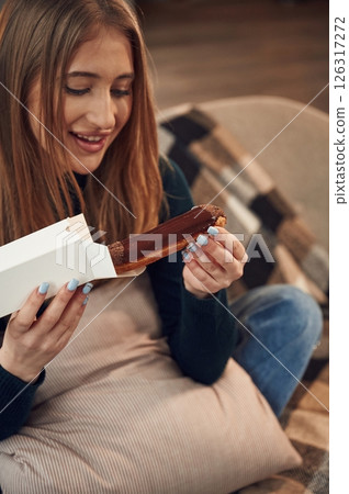 Woman is sitting and taking the sweet dessert from the paper eco box Woman is sitting and taking the sweet dessert from the paper eco box 126317272