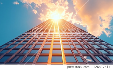 Majestic View of Skyscraper Reaching for Sky with Sunburst and Clouds in the Background Majestic View of Skyscraper Reaching for Sky with Sunburst and Clouds in the Background 126317415