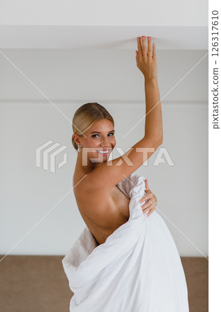 Close-up portrait of seductive young bride in hotel room wrapped in white blanket 126317610