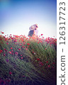 Couple embracing in a romantic and joyful mood, enjoying love and connection in a vibrant poppy field against a bright blue sky background  126317723