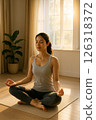 A woman meditating in a room with morning sunlight 126318372