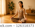 A woman meditating in a room with morning sunlight 126318373
