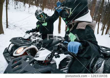 Making high five. Two people are riding ATV in the winter forest 126318436