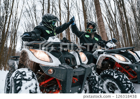 Making high five. Two people are riding ATV in the winter forest 126318438