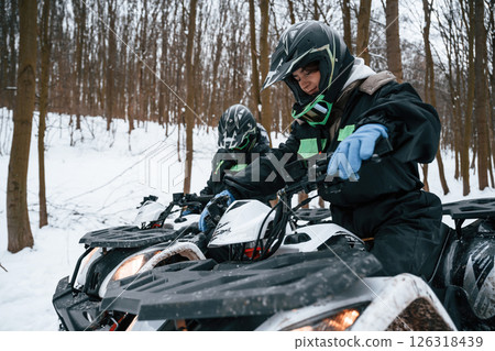 Woman with her friend. Two people are riding ATV in the winter forest 126318439