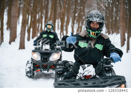 Woman with her friend. Two people are riding ATV in the winter forest 126318441
