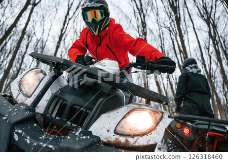 Two people are riding ATV in the winter forest 126318460