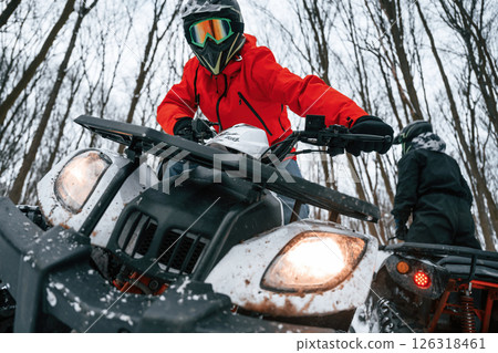 Two people are riding ATV in the winter forest Two people are riding ATV in the winter forest 126318461