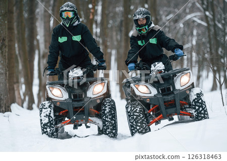 Man and woman are riding ATV in the winter forest 126318463