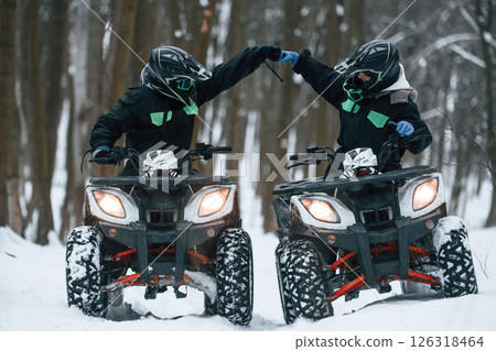 Preparing for the ride. Man and woman are on the ATV in the winter forest Preparing for the ride. Man and woman are on the ATV in the winter forest 126318464