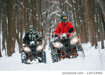 Front view. Two people are riding ATV in the winter forest 126318468