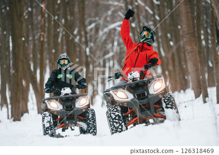 Conception of extreme sports. Two people are riding ATV in the winter forest 126318469