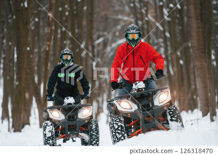 Front view. Two people are riding ATV in the winter forest 126318470