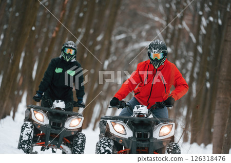 Conception of extreme sports. Two people are riding ATV in the winter forest Conception of extreme sports. Two people are riding ATV in the winter forest 126318476