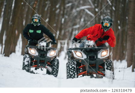 Conception of active recreation. Two people are riding ATV in the winter forest 126318479