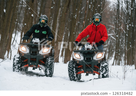 Conception of active recreation. Two people are riding ATV in the winter forest 126318482