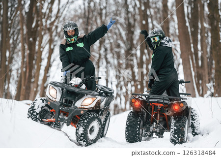 Making gestures. Two people are riding ATV in the winter forest 126318484