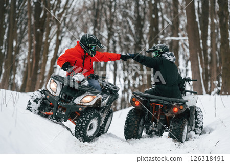 Knocking the fists. Two people are riding ATV in the winter forest Knocking the fists. Two people are riding ATV in the winter forest 126318491