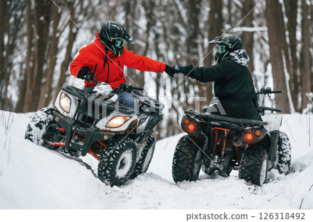 Knocking the fists. Two people are riding ATV in the winter forest 126318492