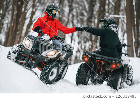 Knocking the fists. Two people are riding ATV in the winter forest 126318493