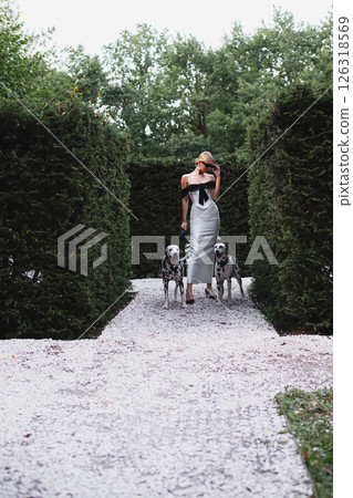 Young beautiful bride in stylish elegant dress posing in park with two dalmatians Young beautiful bride in stylish elegant dress posing in park with two dalmatians 126318569