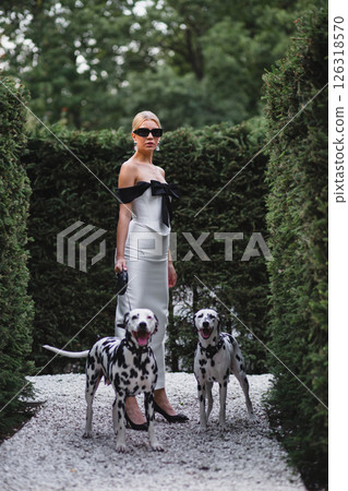 Young beautiful bride in stylish elegant dress posing in park with two dalmatians 126318570