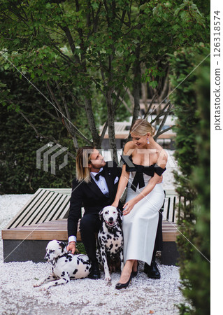 Stylish young beautiful newlywed couple walking at wedding in park with two dalmatians 126318574