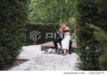 Stylish young beautiful newlywed couple walking at wedding in park with two dalmatians 126318575
