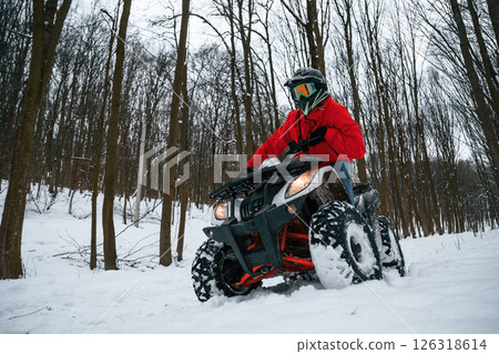 Snow, trees, adventure. Man is riding ATV outdoors in the winter forest 126318614
