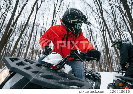 Two people are riding ATV in the winter forest Two people are riding ATV in the winter forest 126318616