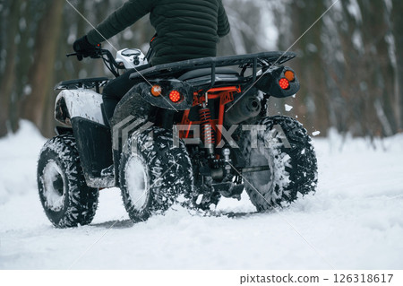 Snow, trees, adventure. Man is riding ATV outdoors in the winter forest Snow, trees, adventure. Man is riding ATV outdoors in the winter forest 126318617