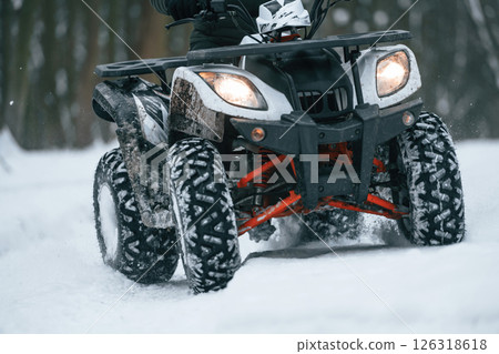 Snow, trees, adventure. Man is riding ATV outdoors in the winter forest 126318618