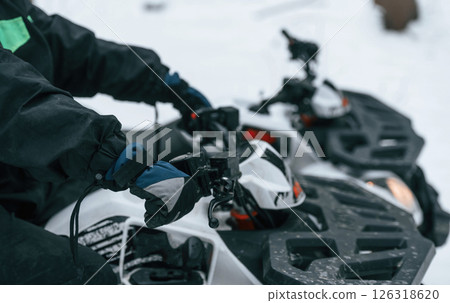 Close up view of the hands and front part of vehicle. Man is riding ATV outdoors in the winter forest 126318620