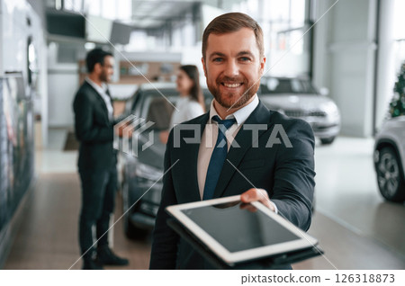 Using graphic tablet. Three people are working together in the car showroom Using graphic tablet. Three people are working together in the car showroom 126318873